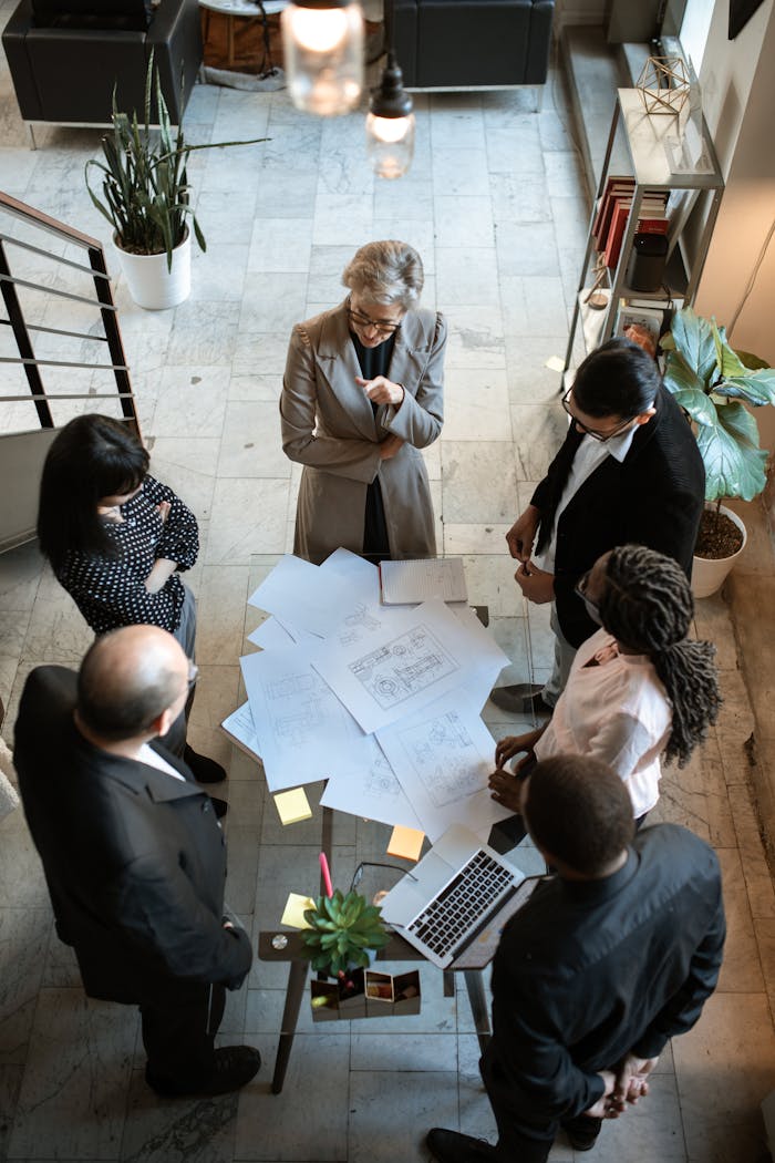 A diverse group of professionals collaborating over documents in a modern office setting.